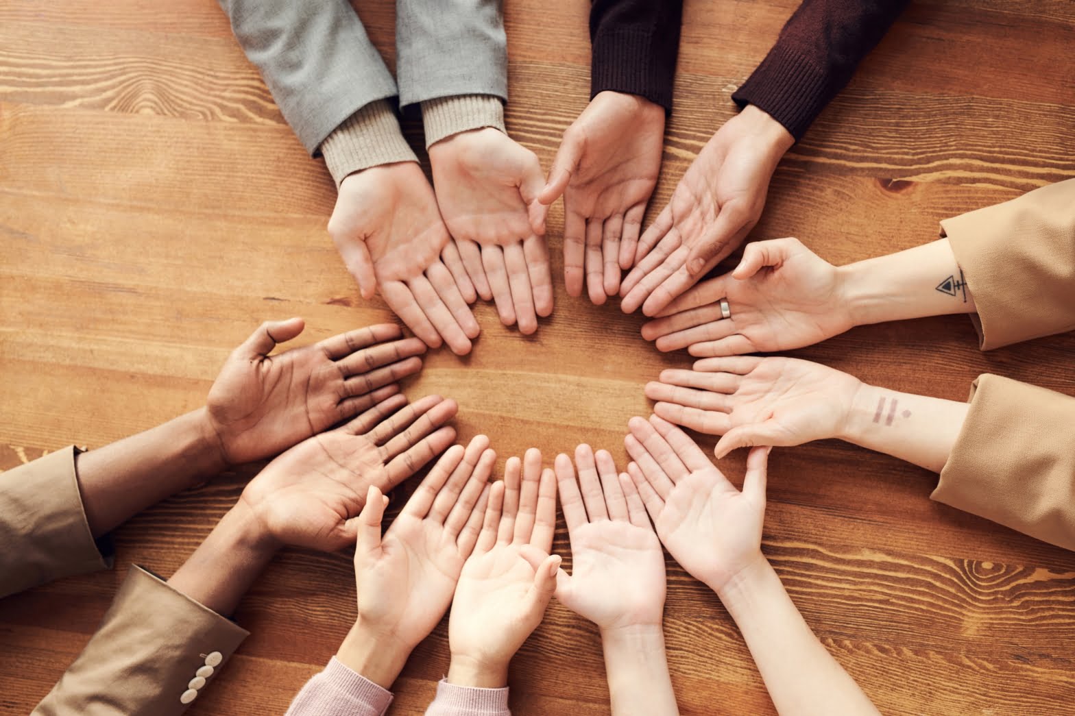 a group of people place their hands in a circle, indicating the help that a group session may provide