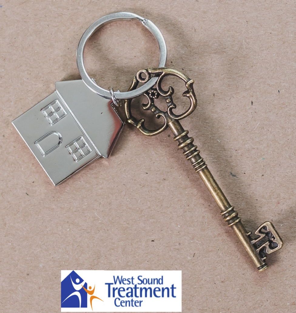 A skeleton key on a house keychain with the West Sound Treatment Center logo represents WSTC recovery housing