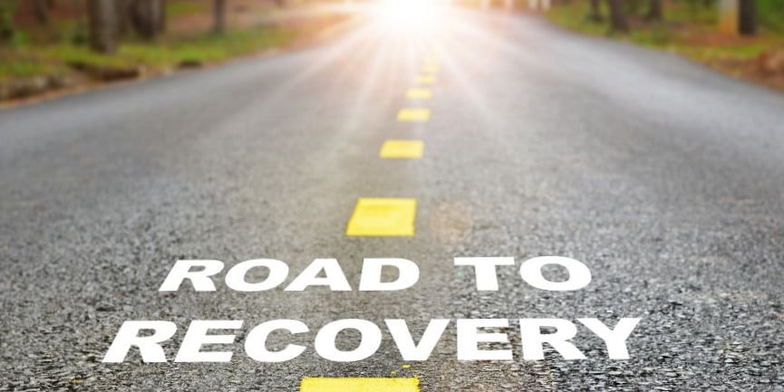 A road with the words "Road to Recovery" on the asphalt