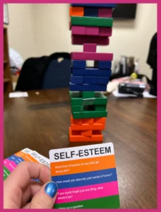 A colorful stacking game in progress with a prompt card suggesting talking points for addiction treatment